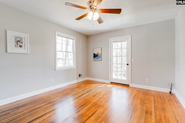 spare room with plenty of natural light, ceiling fan, and light wood-type flooring