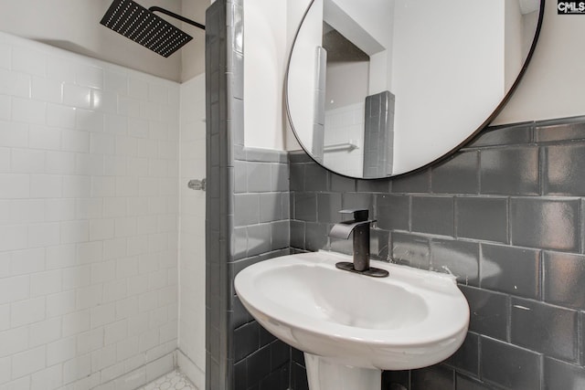 bathroom featuring tiled shower, sink, and tile walls