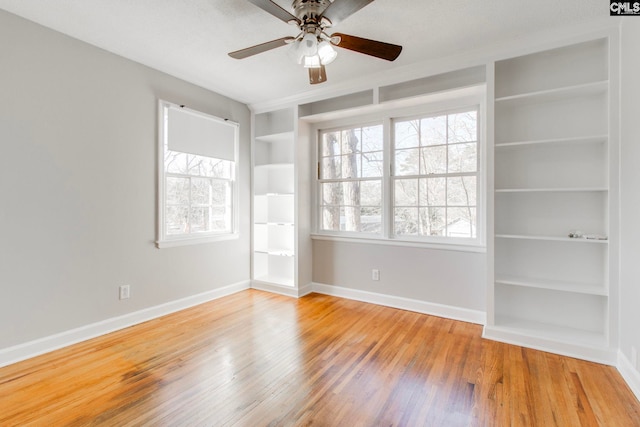 spare room featuring hardwood / wood-style flooring, ceiling fan, and built in shelves