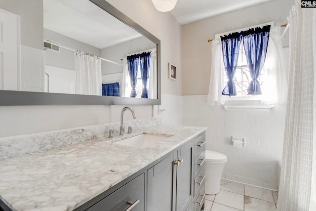 bathroom featuring vanity, toilet, and tile walls