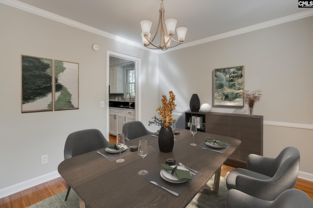 dining area with crown molding, an inviting chandelier, sink, and light wood-type flooring