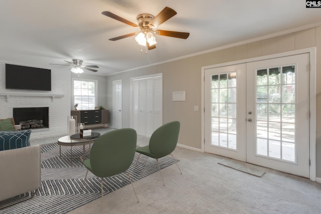 living room featuring french doors, crown molding, ceiling fan, light colored carpet, and a fireplace