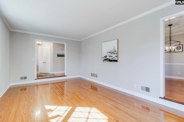 spare room with hardwood / wood-style floors, crown molding, and a chandelier