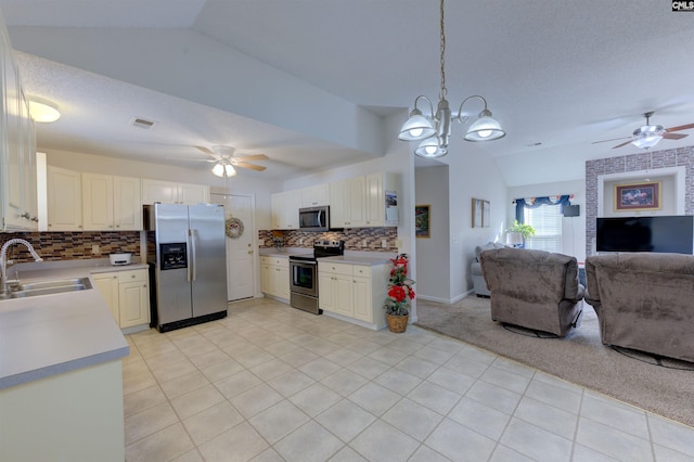 kitchen featuring vaulted ceiling, appliances with stainless steel finishes, pendant lighting, sink, and white cabinets