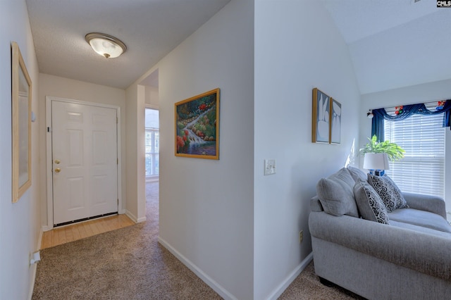 hall featuring vaulted ceiling and carpet