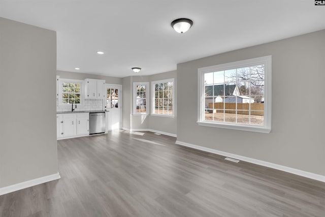 unfurnished living room featuring a healthy amount of sunlight, sink, and hardwood / wood-style floors