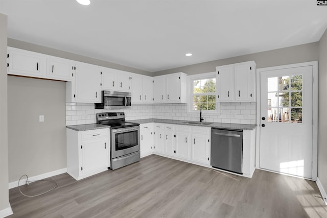 kitchen featuring sink, stone counters, stainless steel appliances, white cabinets, and light wood-type flooring