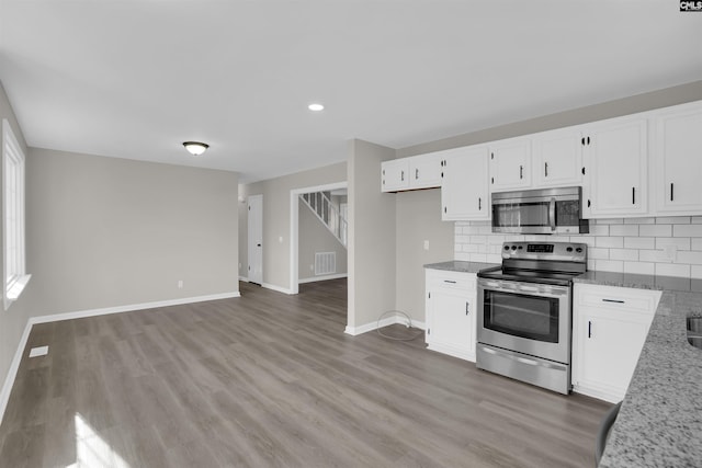 kitchen with white cabinetry, stainless steel appliances, light stone countertops, and tasteful backsplash