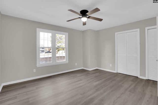 unfurnished bedroom featuring multiple closets, ceiling fan, and light wood-type flooring