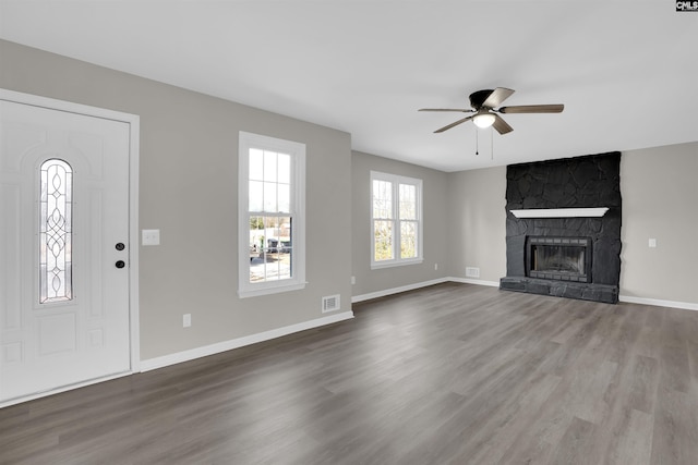 unfurnished living room with hardwood / wood-style flooring, a stone fireplace, and ceiling fan