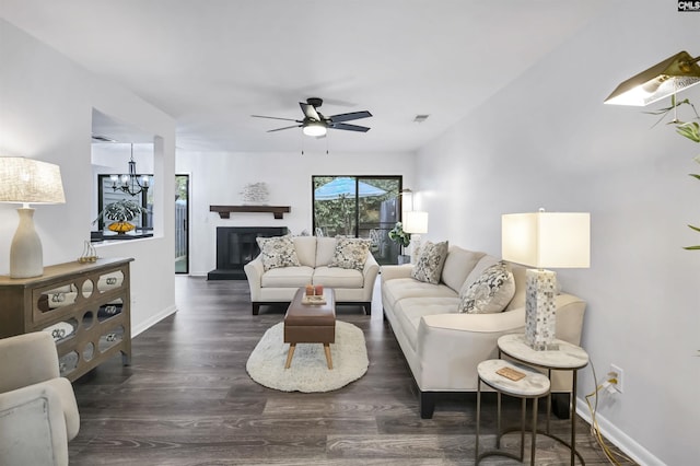 living room with dark wood-type flooring and ceiling fan with notable chandelier