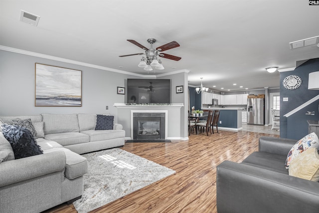 living room featuring crown molding, ceiling fan with notable chandelier, and light hardwood / wood-style floors