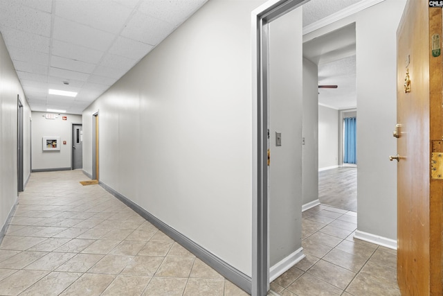 hallway with light tile patterned flooring and a drop ceiling