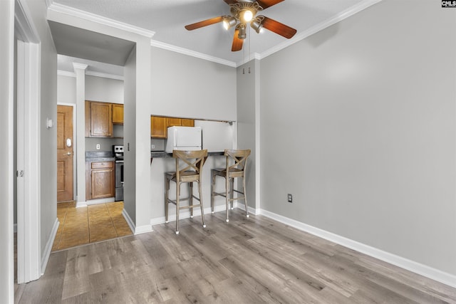 interior space featuring light hardwood / wood-style flooring, stainless steel range with electric stovetop, a kitchen breakfast bar, white refrigerator, and ornamental molding