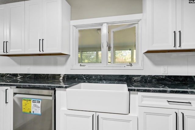 kitchen with white cabinetry, stainless steel dishwasher, dark stone counters, and sink