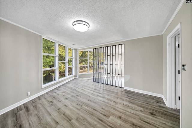 empty room with hardwood / wood-style flooring, ornamental molding, and a textured ceiling