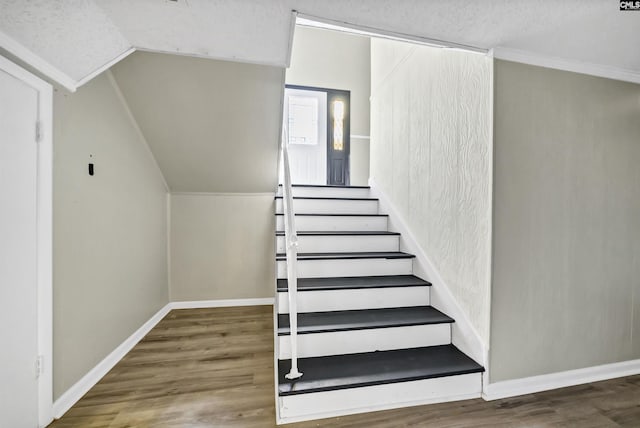 stairway with wood-type flooring and vaulted ceiling