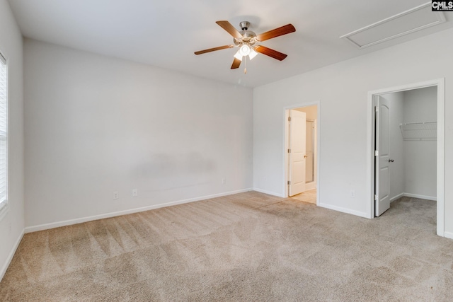 unfurnished bedroom with ensuite bath, a spacious closet, light carpet, a closet, and ceiling fan