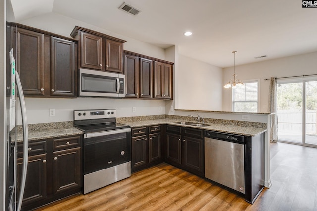 kitchen with sink, stainless steel appliances, kitchen peninsula, and light wood-type flooring