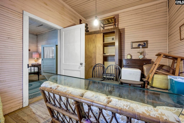 dining space with light wood-type flooring and wooden walls