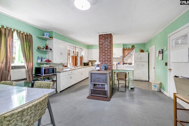 kitchen with white refrigerator, a center island, white cabinets, and concrete floors