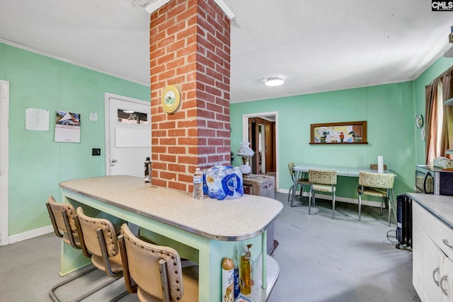 kitchen with white cabinetry, crown molding, and a kitchen bar