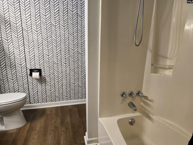 bathroom featuring wood-type flooring, shower / washtub combination, and toilet