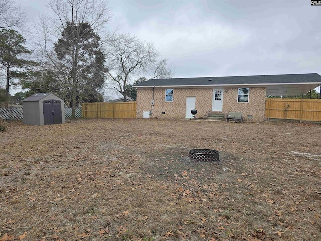 rear view of property with a shed and a fire pit