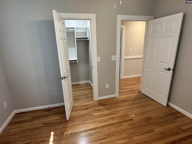 unfurnished bedroom with wood-type flooring, a spacious closet, and a closet