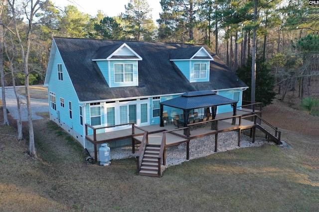 back of property with a gazebo, a deck, and a lawn