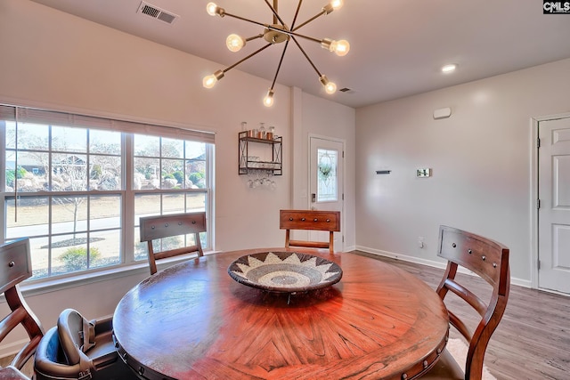 dining room featuring a healthy amount of sunlight, a chandelier, and light wood-type flooring