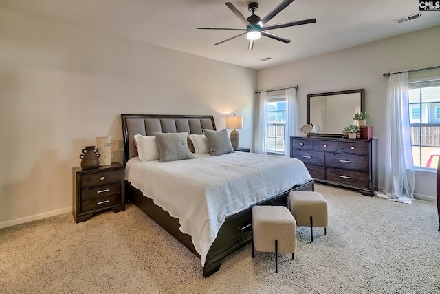 bedroom featuring ceiling fan, multiple windows, and light carpet