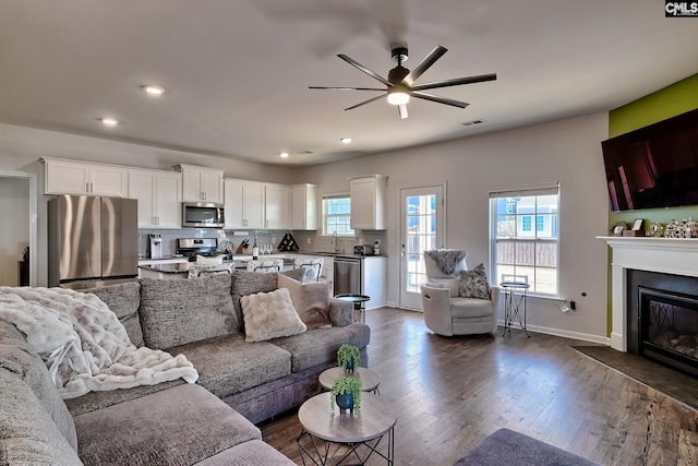 living room featuring dark hardwood / wood-style flooring, sink, and ceiling fan