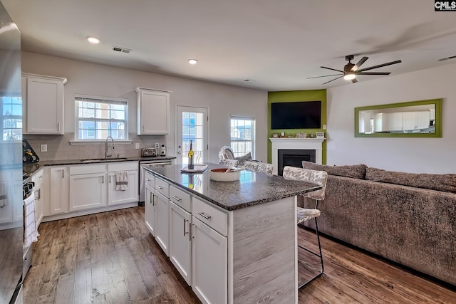 kitchen with a breakfast bar, sink, white cabinetry, tasteful backsplash, and a kitchen island