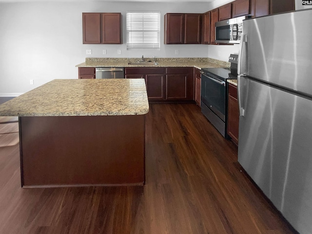 kitchen with sink, dark hardwood / wood-style floors, a kitchen island, stainless steel appliances, and light stone countertops