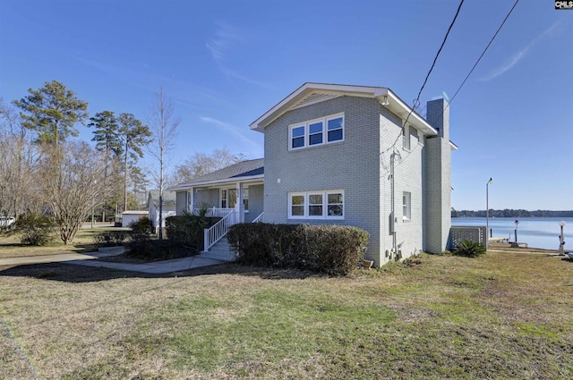 view of front of home featuring covered porch, a front lawn, and a water view