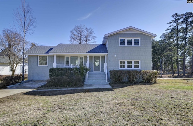 view of front facade featuring covered porch, brick siding, and a front yard