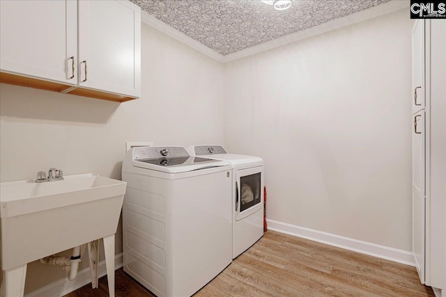 laundry room featuring sink, cabinets, ornamental molding, washing machine and clothes dryer, and light wood-type flooring