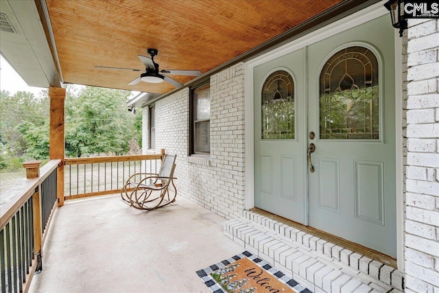 view of exterior entry featuring a porch and ceiling fan