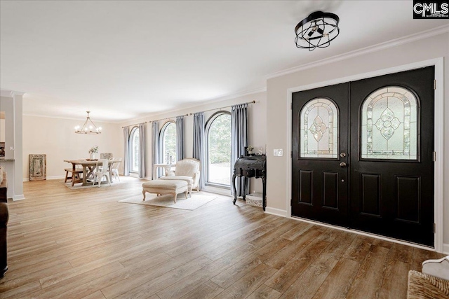 foyer entrance with crown molding, baseboards, french doors, wood finished floors, and a notable chandelier