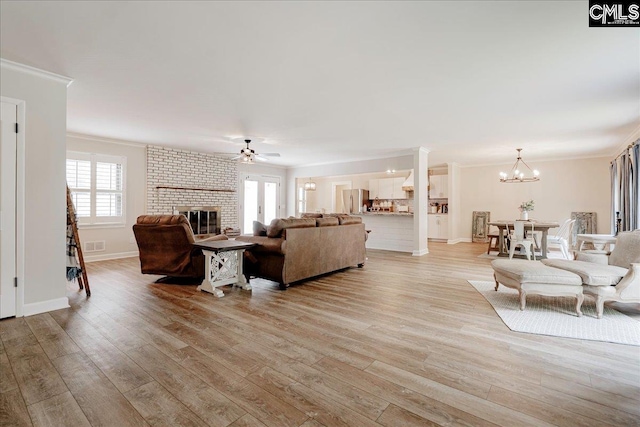 living area with a fireplace, crown molding, light wood-style floors, and a healthy amount of sunlight