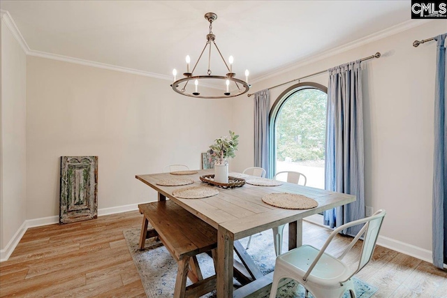 dining area featuring crown molding, an inviting chandelier, and light hardwood / wood-style floors