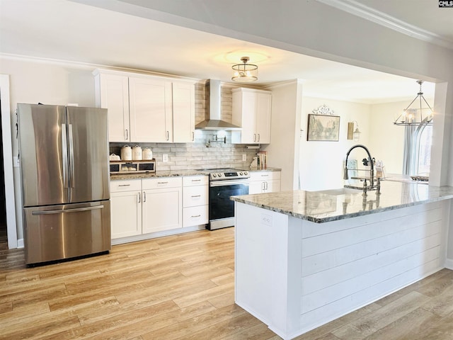 kitchen with stainless steel appliances, ornamental molding, wall chimney range hood, and white cabinets