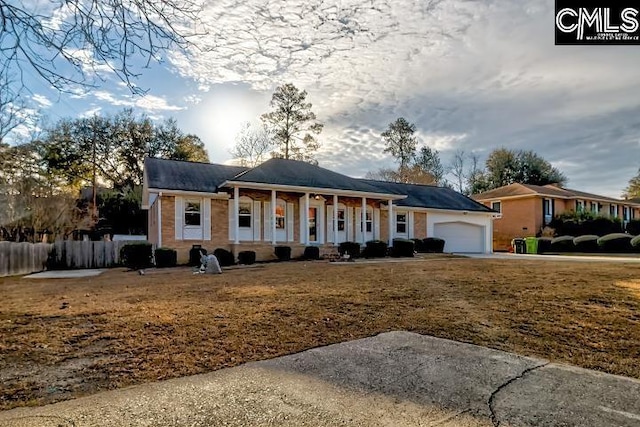 ranch-style house featuring a garage, a front yard, and covered porch