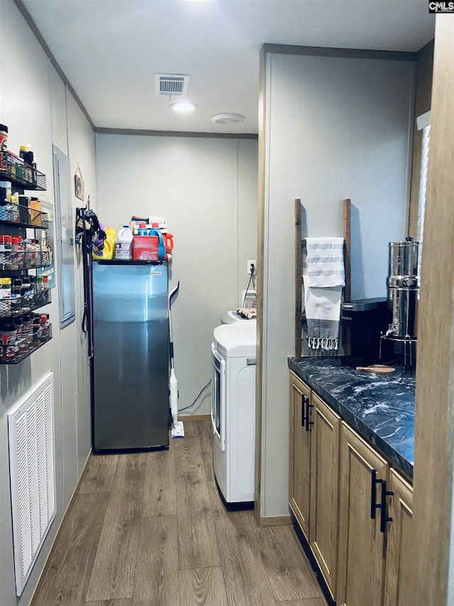 clothes washing area featuring hardwood / wood-style floors, washer / clothes dryer, and cabinets