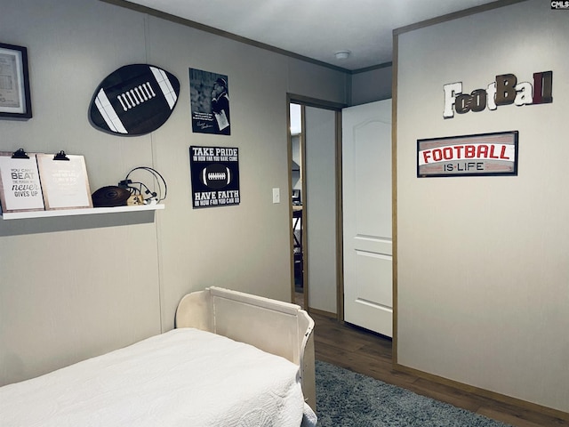 bedroom with ornamental molding and dark hardwood / wood-style floors