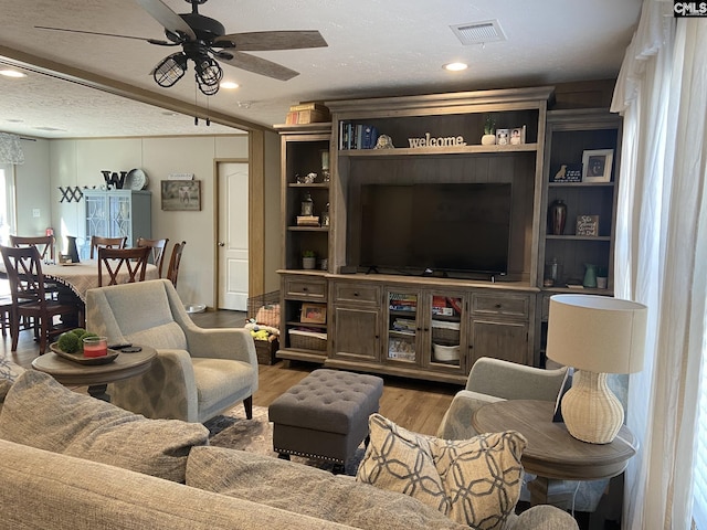 living room with ceiling fan, wood-type flooring, and a textured ceiling