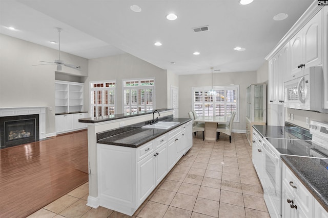 kitchen featuring white appliances, decorative light fixtures, sink, and white cabinets