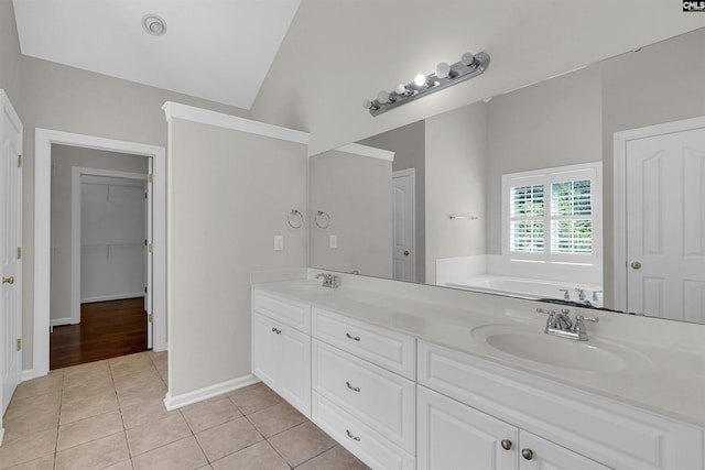 bathroom featuring vanity, a bathtub, vaulted ceiling, and tile patterned floors