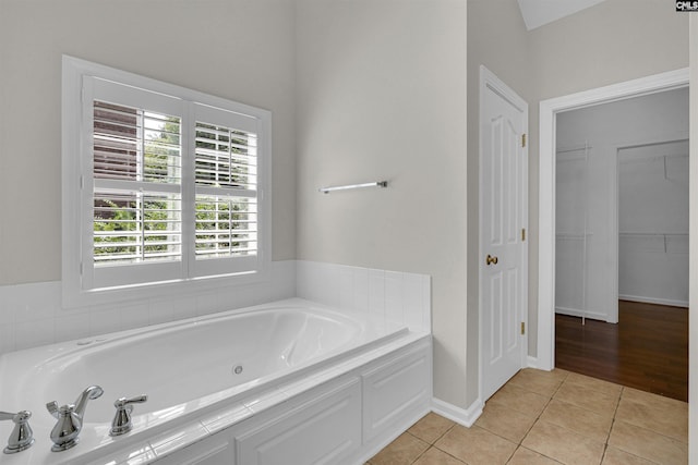 bathroom with tiled tub and tile patterned floors